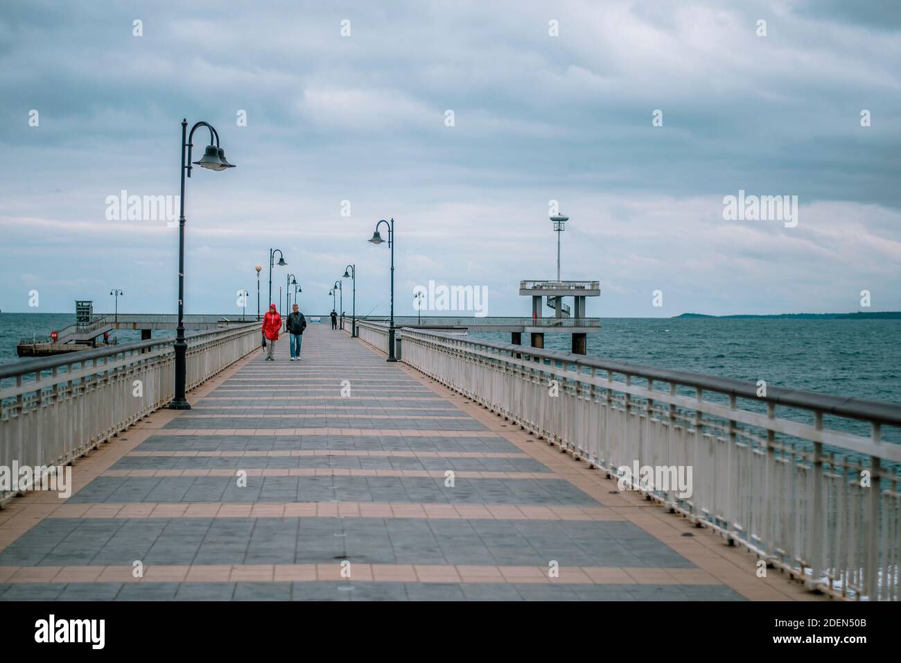 Ein Paar, das auf einer Brücke im Meer spazieren geht. Winter Herbstsaison. Stockfoto