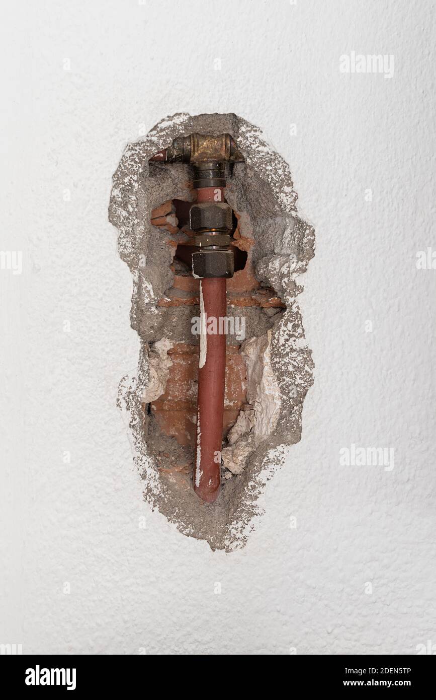 Wasserrohre durch ein Loch in der Wand gesehen Stockfoto