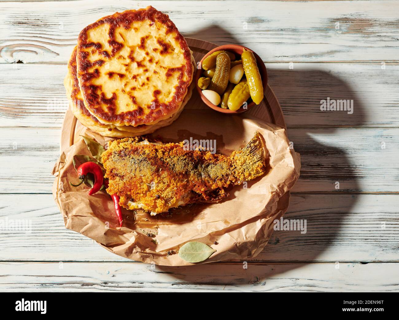 Gebratener Fisch in Papier eingewickelt mit leckeren Pfannkuchen Stockfoto