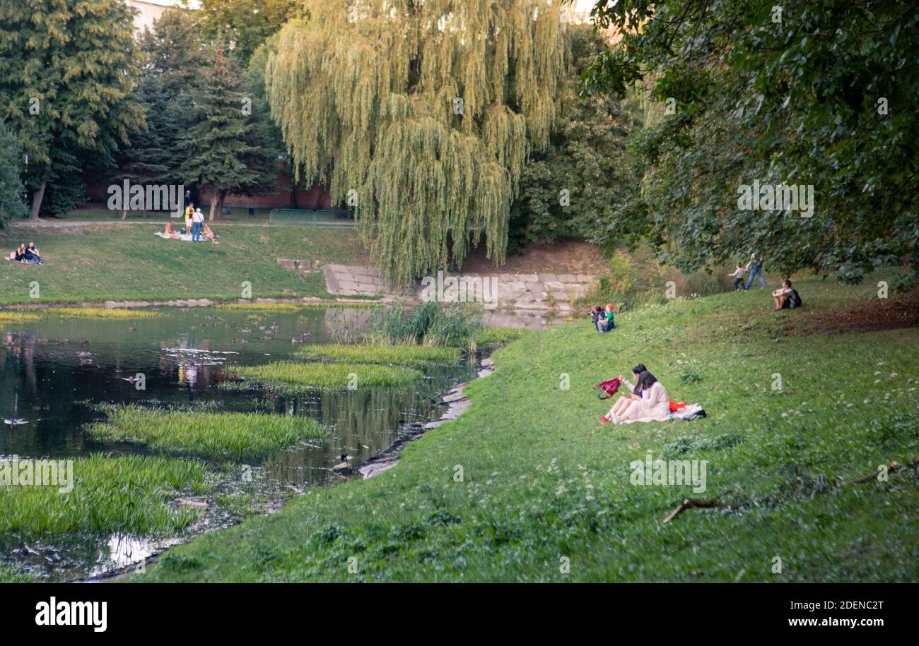 Lviv, Ukraine - 28. August 2020: Menschen, die in der Nähe von See in der Stadt öffentlichen Park Kopie Platz. Blick auf Enten Stockfoto