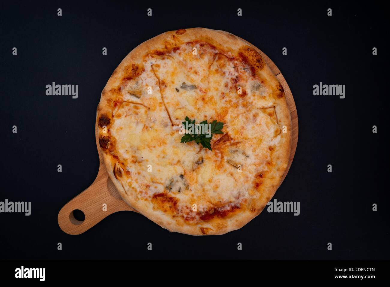 Ein Blick von oben auf eine frisch gebackene leckere kitschige Pizza Mit Petersilie auf einem hölzernen Schneidebrett Stockfoto