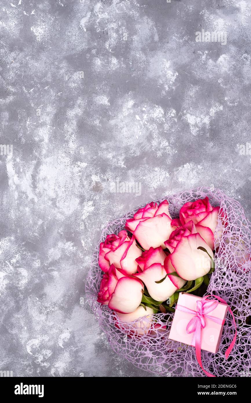 Rot Weiss rose flower bouquet mit rosafarbenen Geschenkbox auf Tisch aus Stein. Das Konzept einer Postkarte zu Muttertag, 8. März, des heiligen Valentinstag oder Geburt Stockfoto