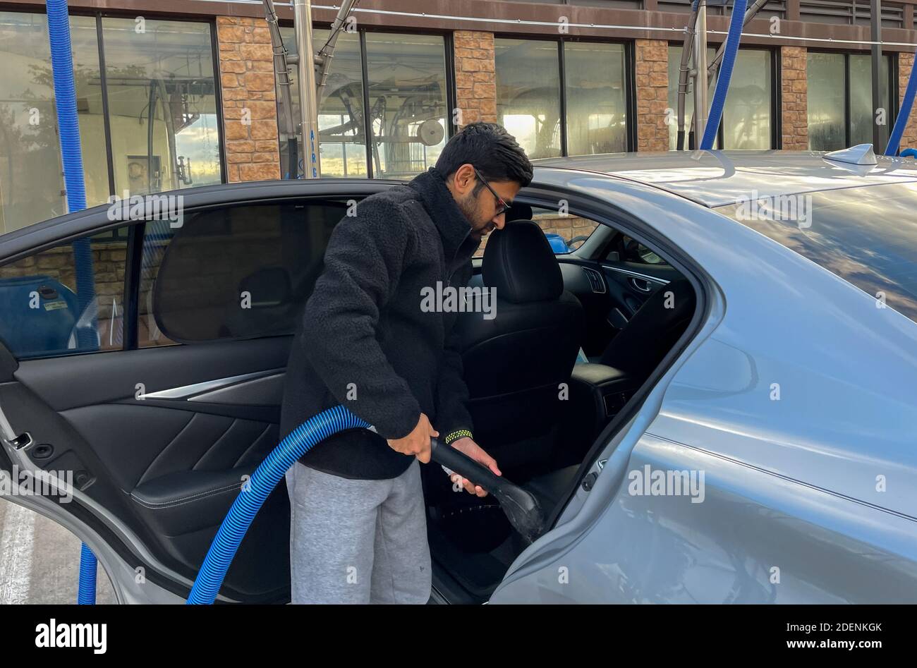 McKinney, TX / USA - 30. November 2020: Nahaufnahme eines Mannes, der mit dem Vakuumschlauch sein Auto auf dem Selbstbedienungs-Vakuummarkplatz saugt Stockfoto