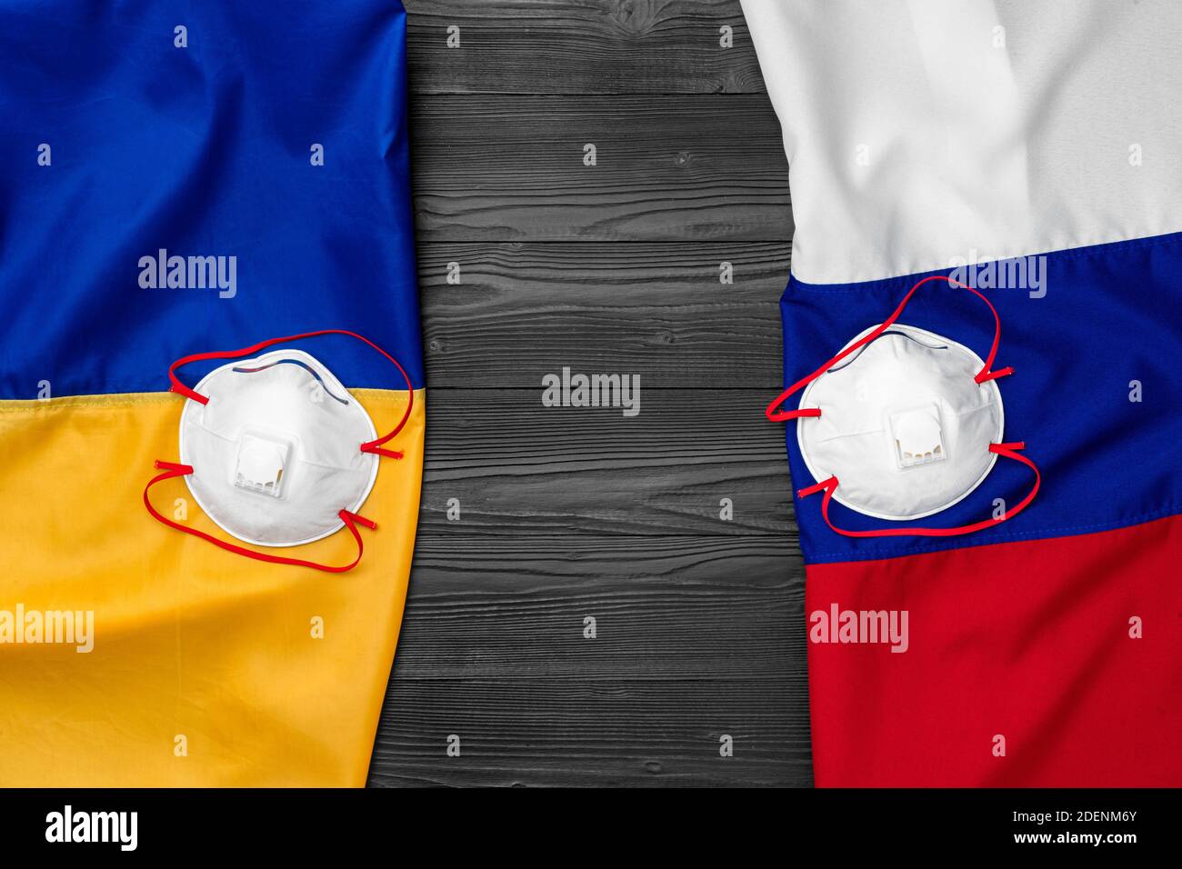 Flaggen von Russland und der Ukraine auf hölzernen Hintergrund mit medizinischen Masken Stockfoto