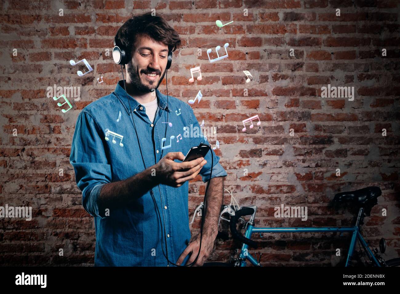 Junge Millennials hören Musik mit Handy und Kopfhörer. 3D Musiknoten um ihn herum. Stockfoto