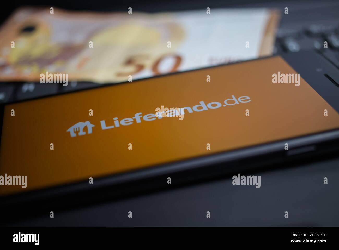 Viersen, Deutschland - 9. April. 2020: Nahaufnahme des Handybildschirms mit Logo-Schriftzug des Lieferando Food Delivery Service auf Computertastatur, verschwommen Stockfoto
