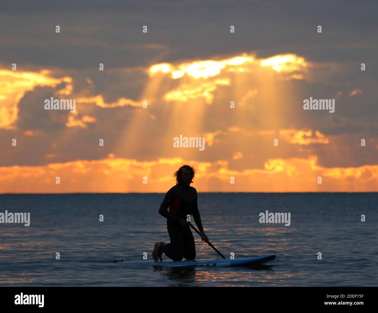 Surfer warten auf dem Wasser auf eine Welle in der Sonnenuntergang Stockfoto