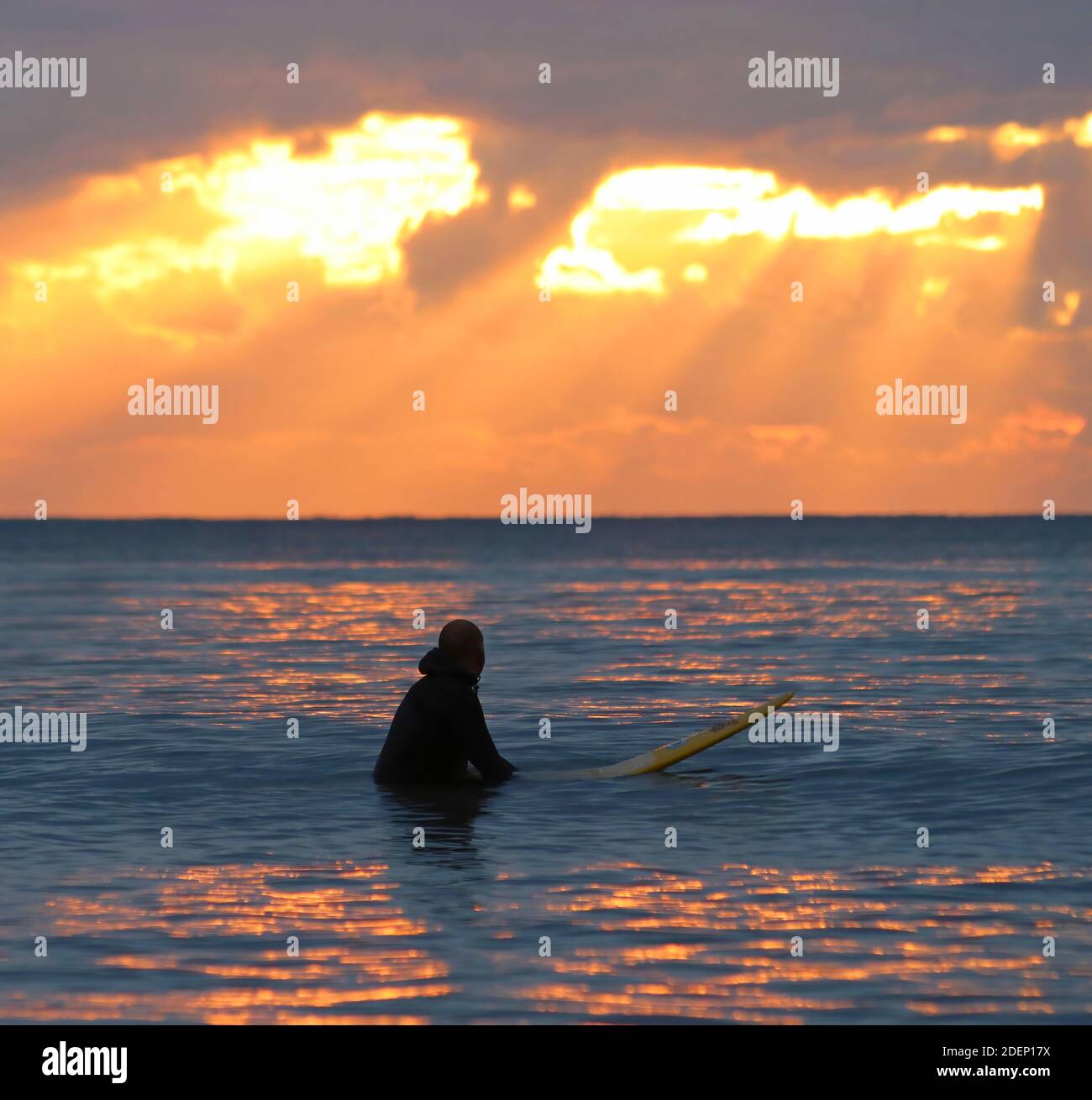 Surfer warten auf dem Wasser auf eine Welle in der Sonnenuntergang Stockfoto