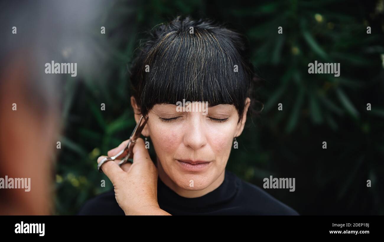 Junge Frau bekommt ihre Frisur. Der Friseur benutzt die Schere. Stockfoto