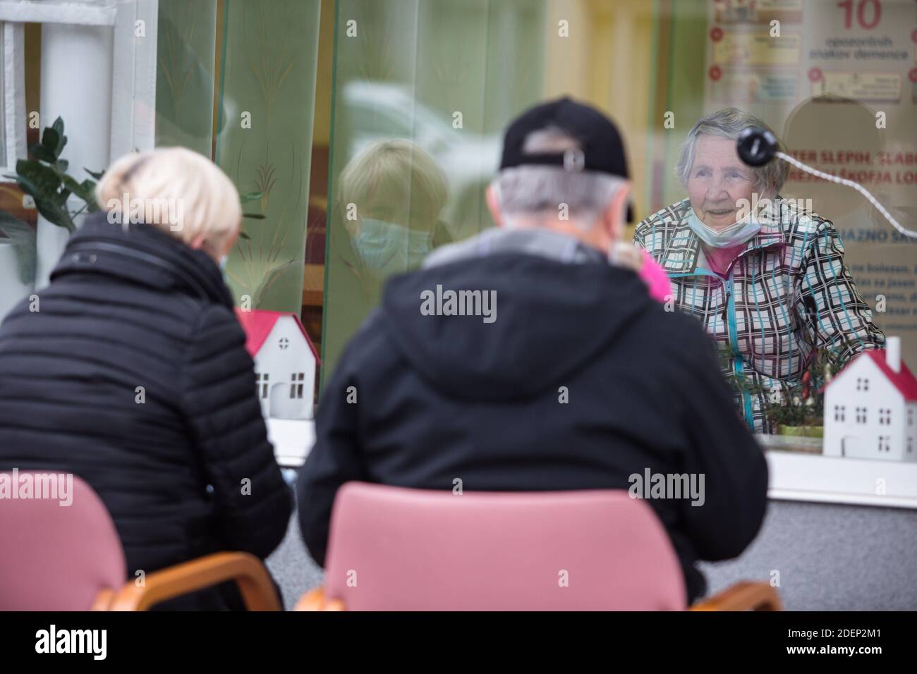 Eine Familie, die während ihres Besuchs in einem Altenheim ein zwei-Wege-Kommunikationssystem auf einem Fenster installiert hat. Pflegeheime in Slowenien begannen, kontaktlose Besuche zu ermöglichen, nachdem zwei Monate lang die zweite Welle der covid-19-Epidemie in Slowenien streng gesperrt war. Die Lage des Coronavirus in Slowenien ist eine der schlimmsten in der Welt, was die Todesfälle pro Kopf betrifft. Pflegeheime wurden in der ersten Welle am schlimmsten getroffen und nehmen wieder einen großen Schlag. Stockfoto