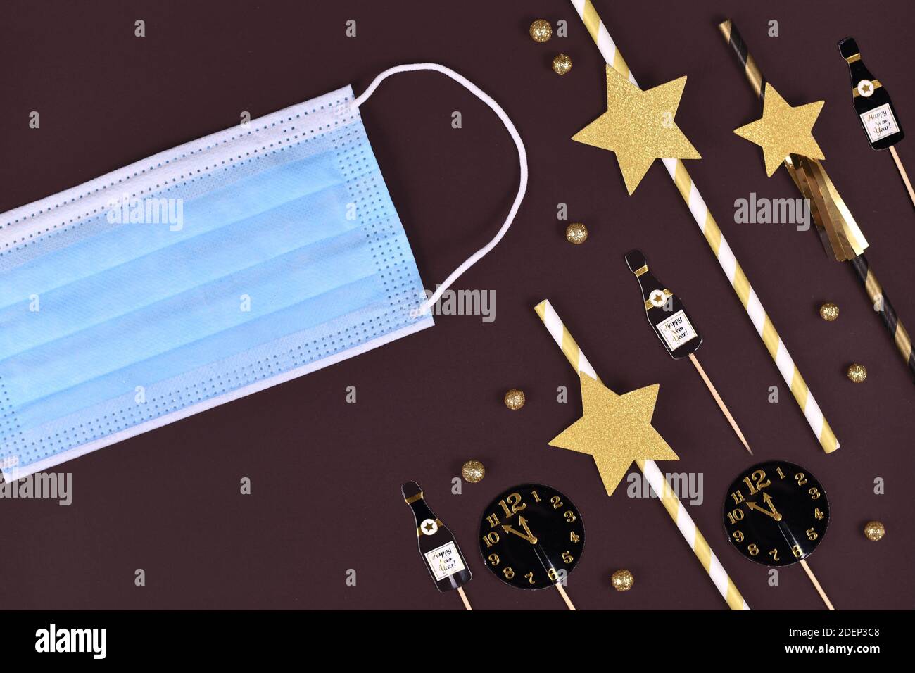 Konzept für Neujahrsfeier in Corona Virus Zeiten mit silvester Party Dekoration mit medizinischer Gesichtsmaske auf dunklem Hintergrund Stockfoto
