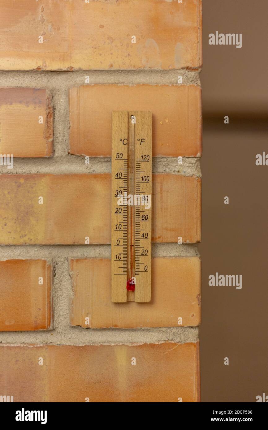 Hölzernes Thermometer auf einer Ziegelwand Stockfoto