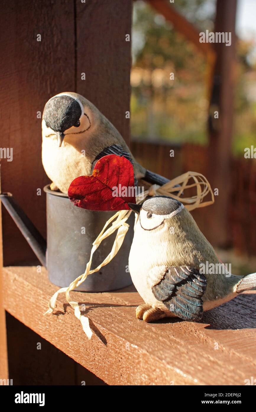 Keramische Gartenfigur eines Paares Vögel mit Herz bei sonnigem Wetter.Gruß valentinstag, Hochzeit, Mama Tageskarte.Herbst Herbst ziemlich sweety Szene. Stockfoto