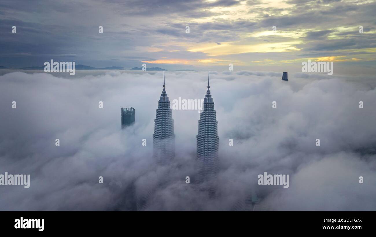 WOLKIGER SONNENAUFGANG IN DEN PETRONAS TWIN TOWERS IN KUALA LUMPUR, MALAYSIA Stockfoto