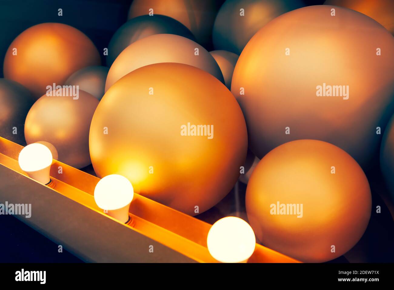 Goldene farbige Kugeln durch elektrische Lampen beleuchtet. Modernes Design Hintergrund Stockfoto