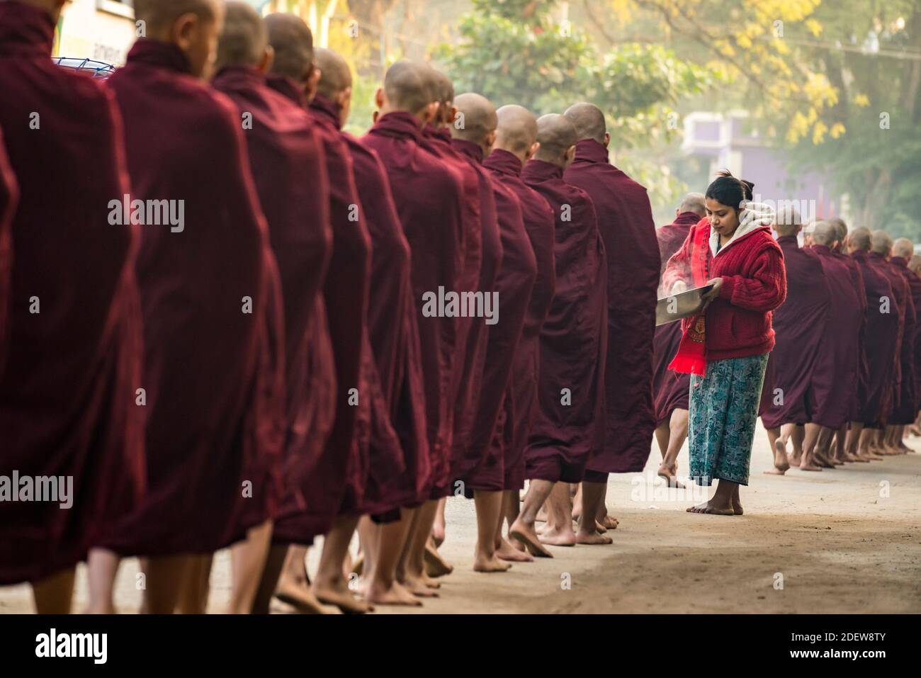 Burmesische Frau, die in der Schlange stehenden Mönchen, Nyaung U, Myanmar, gedämpften Reis gibt Stockfoto