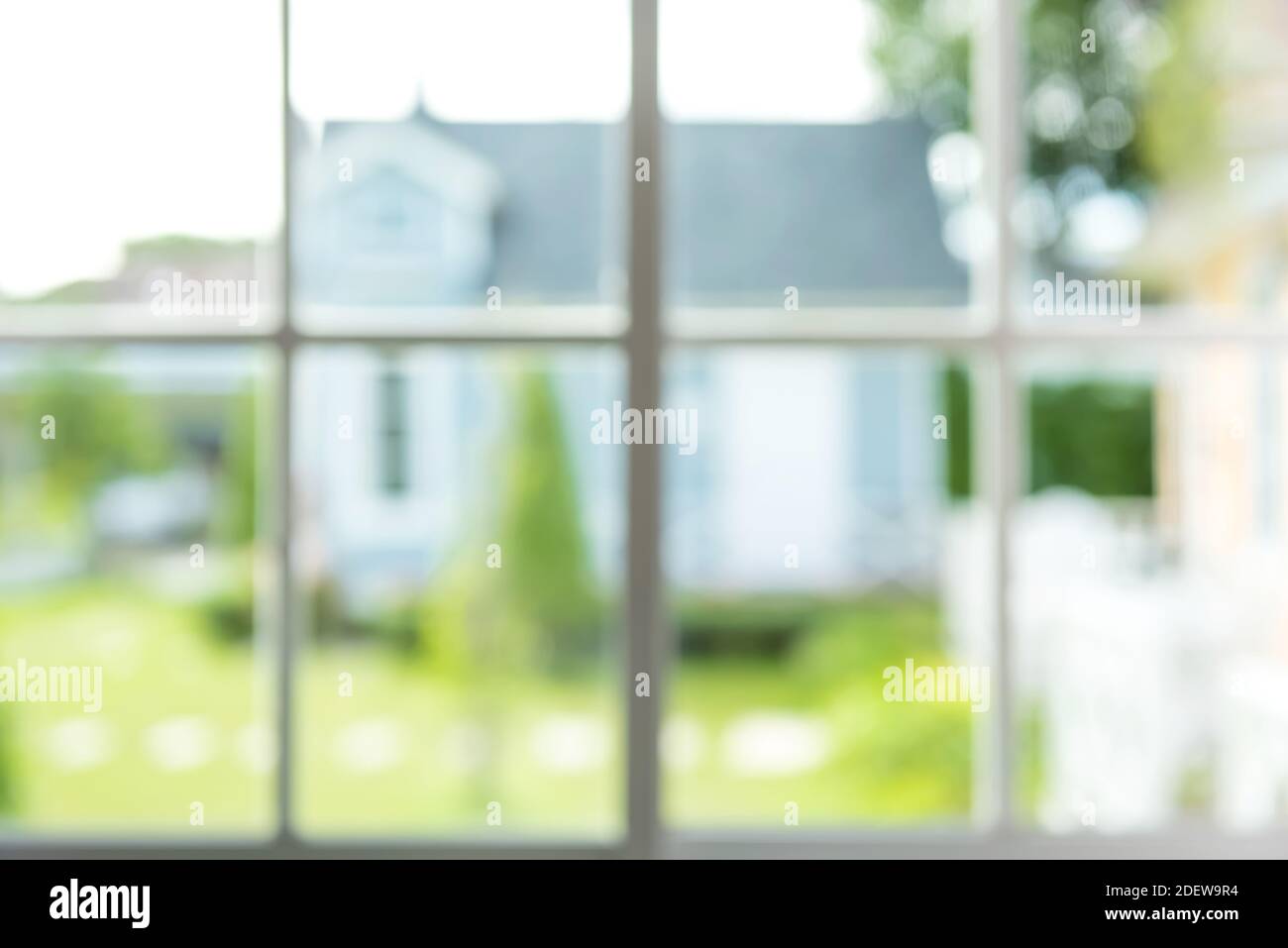 Verschwommenes Bild von grünem Garten und einem Haus, Blick vom Fenster - abstrakter Hintergrund Stockfoto