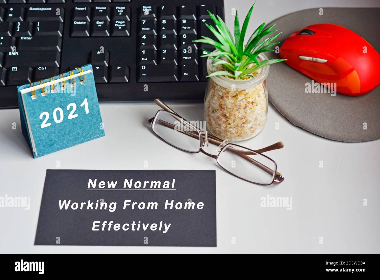 Home Schreibtisch mit Schreibtisch, Kalender 2021, andere Arbeitsmittel und Text auf schwarzer Note geschrieben. Neue Normalität, effektiv von zu Hause aus arbeiten Stockfoto