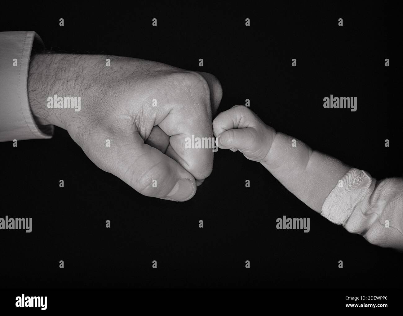 Vater und Baby berühren die Fäuste auf schwarzem Hintergrund Stockfoto