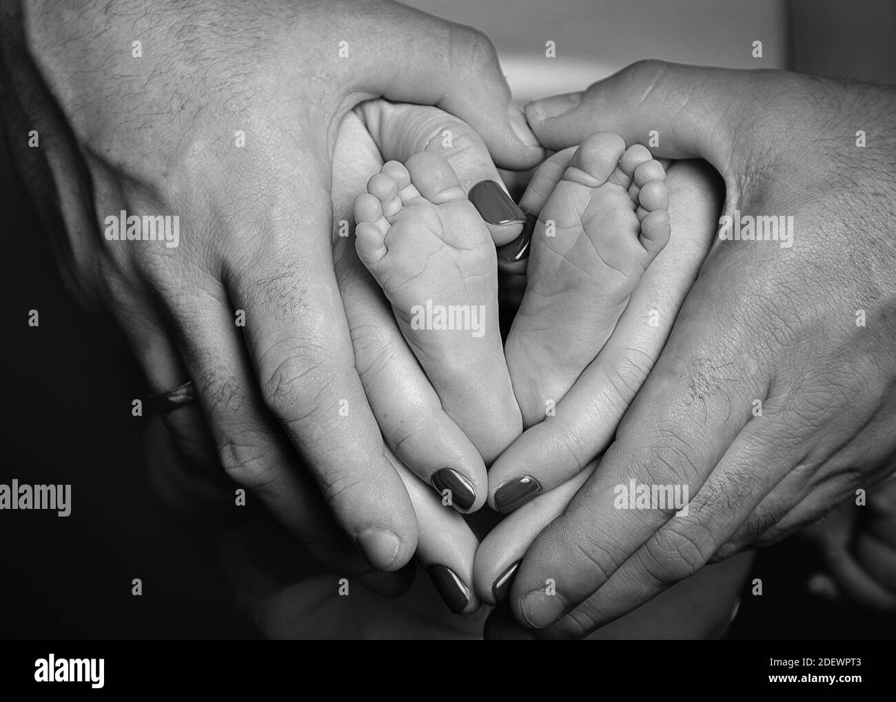 Schwarz-weiß-Bild von Neugeborenen, Vater und Mutter halten Babys Füße bilden eine Herzform Stockfoto