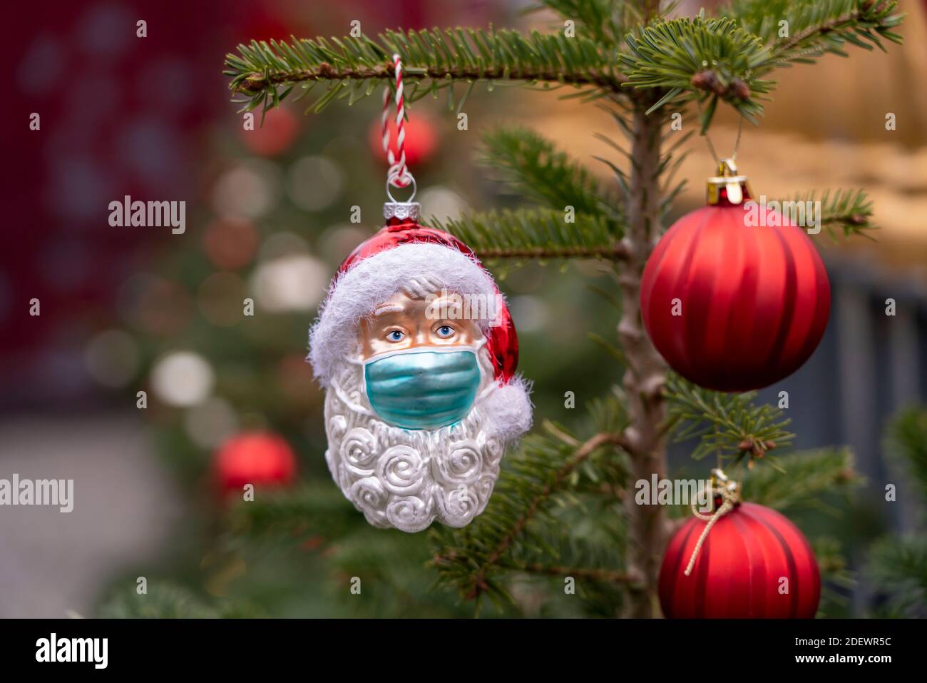 Symbolisches Bild von Weihnachten in der Corona-Krise, Vater Weihnachtsfigur, Weihnachtsmann, Weihnachtsbaum Dekorationen, mit Mund-Nase-Maske, Alltag ma Stockfoto