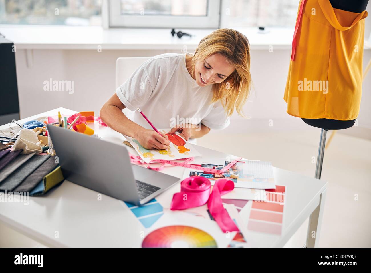 Lächelnder Modedesigner skizziert mit einem Bleistift Stockfoto