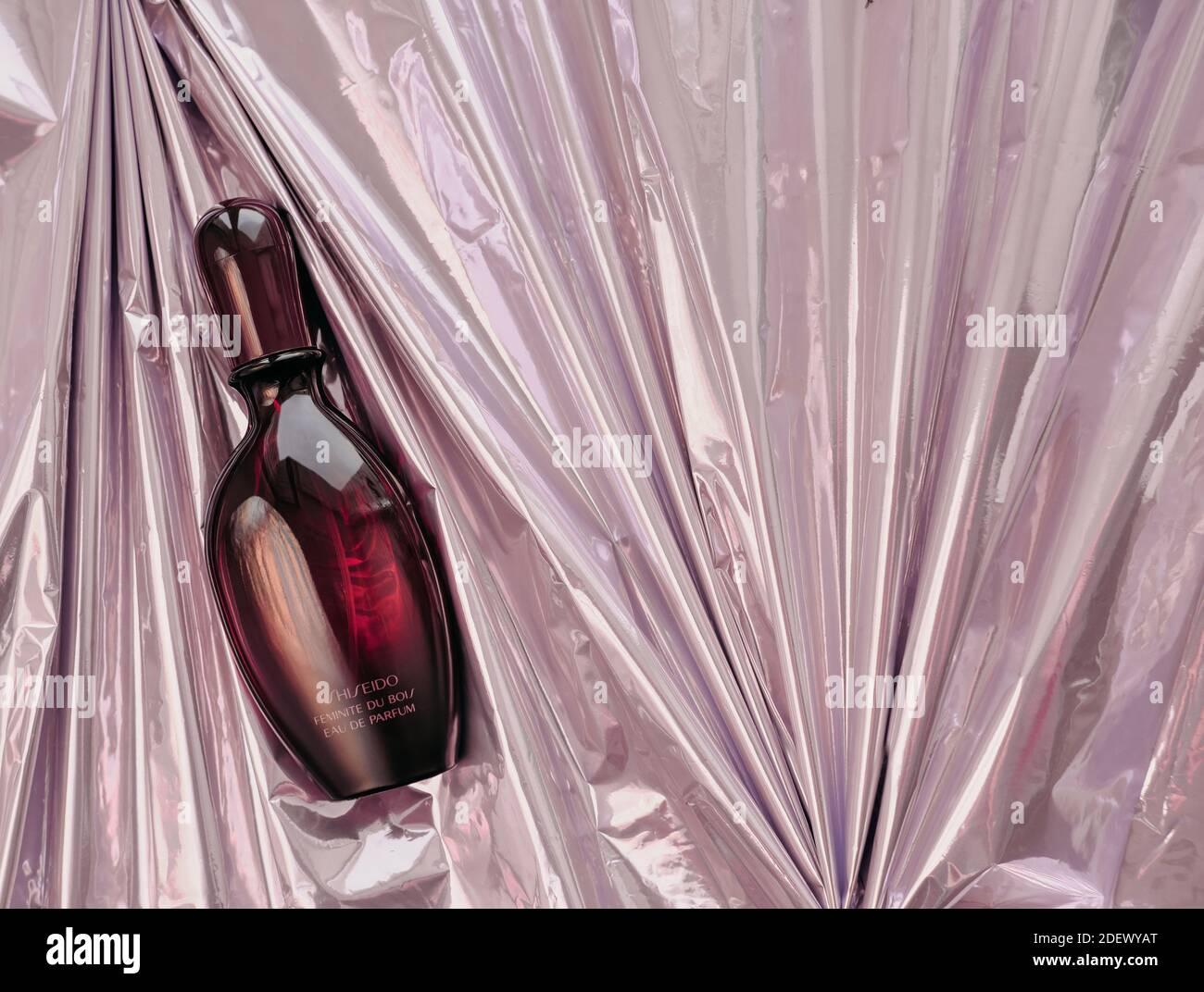 Eine Flasche Parfüm Shiseido Feminite du Bois auf einem pinken metallischen Faltenpapier. Weibliches orientalisches Parfüm für den Winter. Produktion eingestellt. Stockfoto