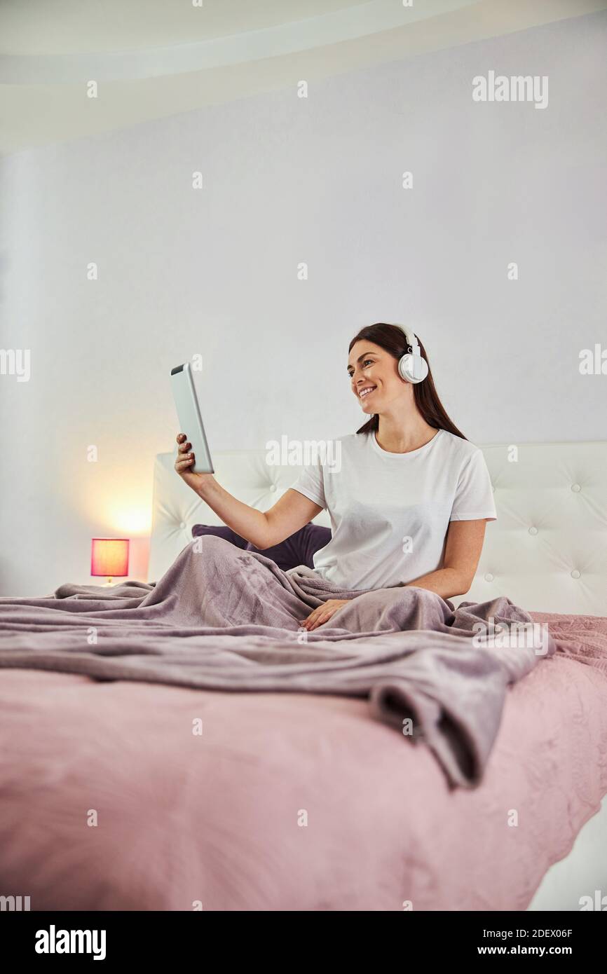 Hausfrau mit einem Tablet für die Kommunikation aus ihrem Schlafzimmer Stockfoto