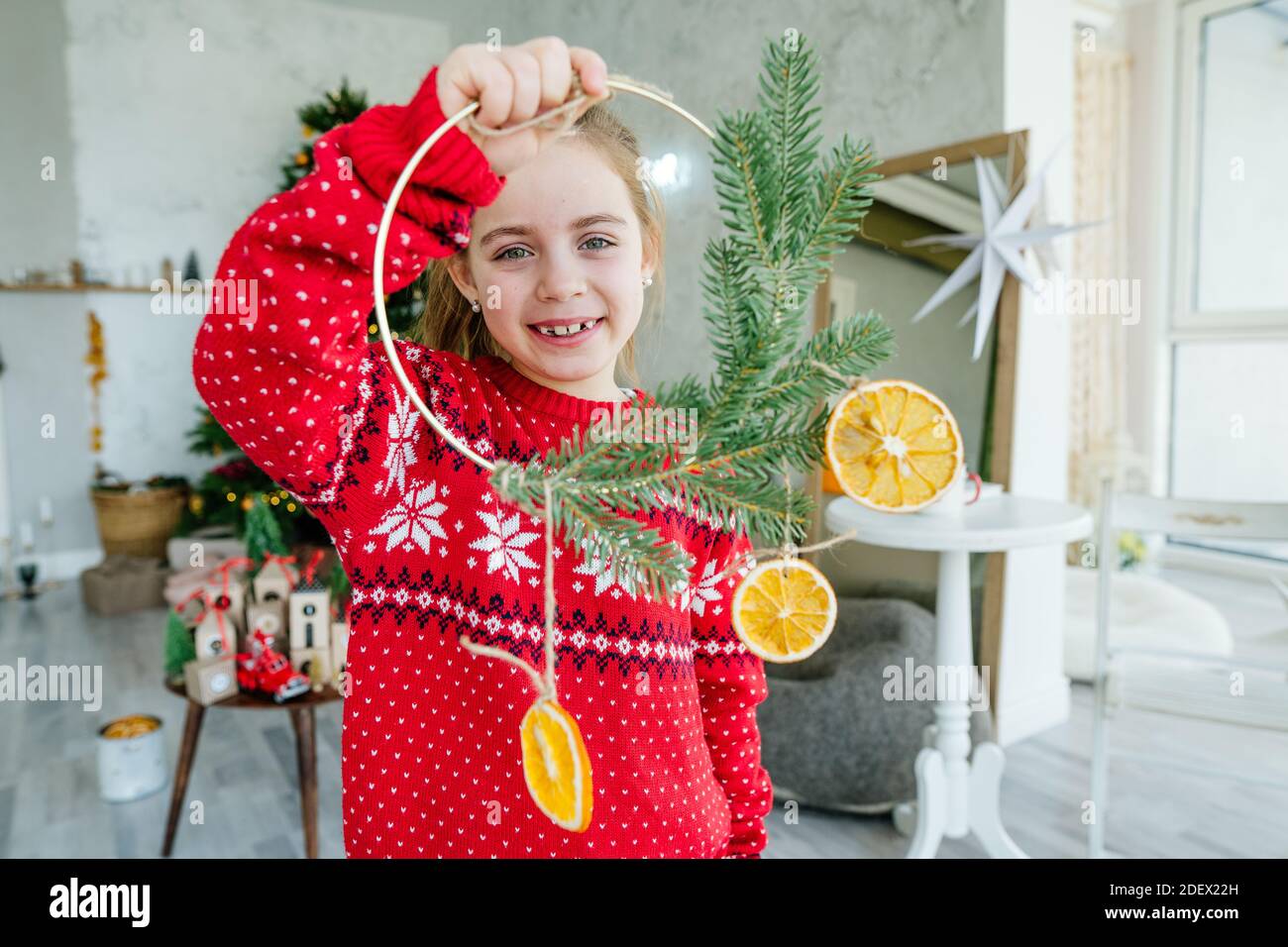 Mädchen suchen werfen handgemachte Weihnachtskranz mit getrockneten Orangen in Das Zimmer Stockfoto