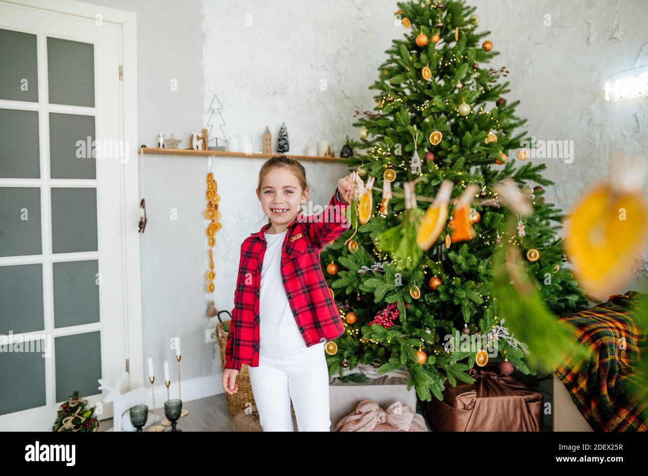 Mädchen hält Girlande mit trockenen Zitrusfrüchten dekoriert Zimmer für Weihnachten Stockfoto