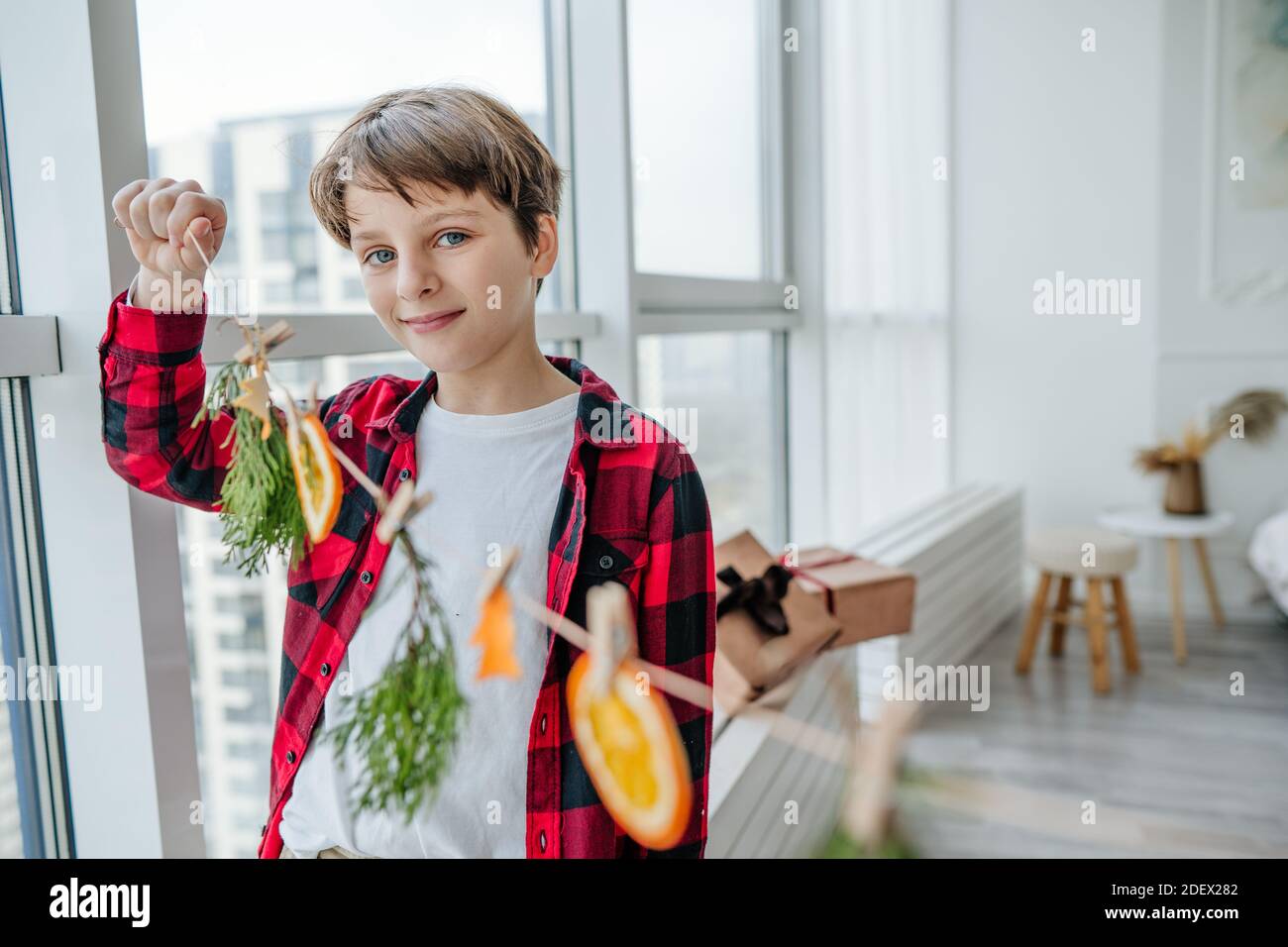 Junge hält Girlande mit trockenen Zitrusfrüchten dekoriert Zimmer für Weihnachten Stockfoto