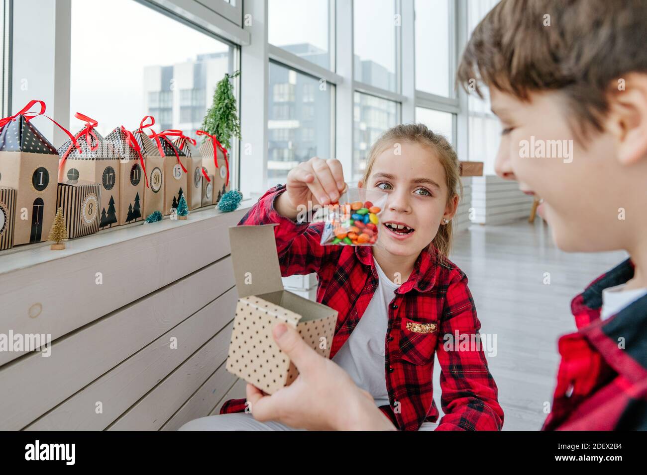 Junge und Mädchen Eröffnung Weihnachten handgemachte Adventskalender mit Süßigkeiten in einem Haus Form, um die Tage bis Weihnachten im Zimmer Countdown. Stockfoto