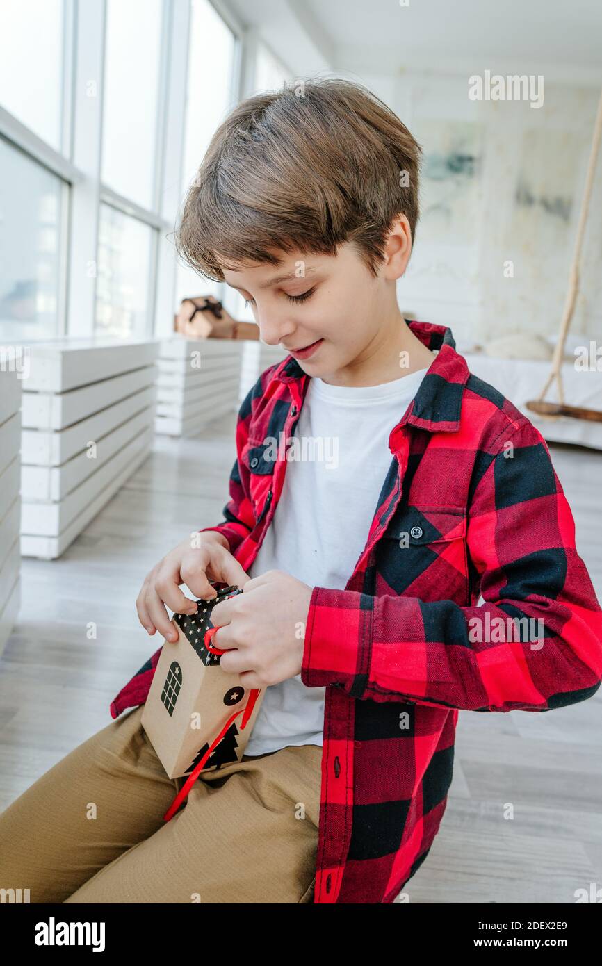 Junge Eröffnung Weihnachten handgemachte Adventskalender in einer Hausform, um die Tage bis Weihnachten im Zimmer Countdown. Stockfoto