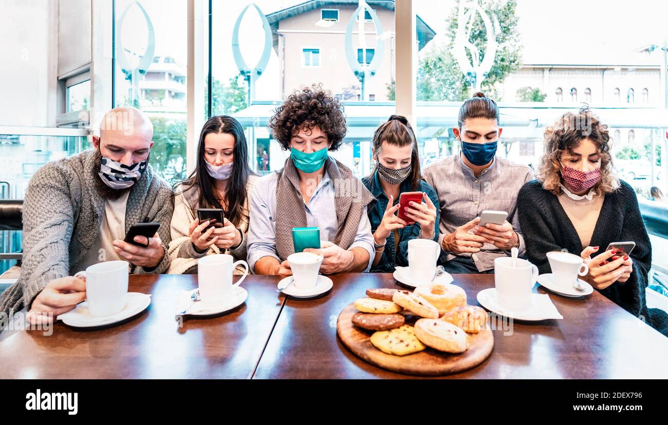 Personen, die Smartphones an der Kaffeebar benutzen, die von abgedeckt sind Gesichtsmasken - Neue normale Lifestyle-Konzept mit besorgten Freunden Video-Nachrichten online ansehen Stockfoto