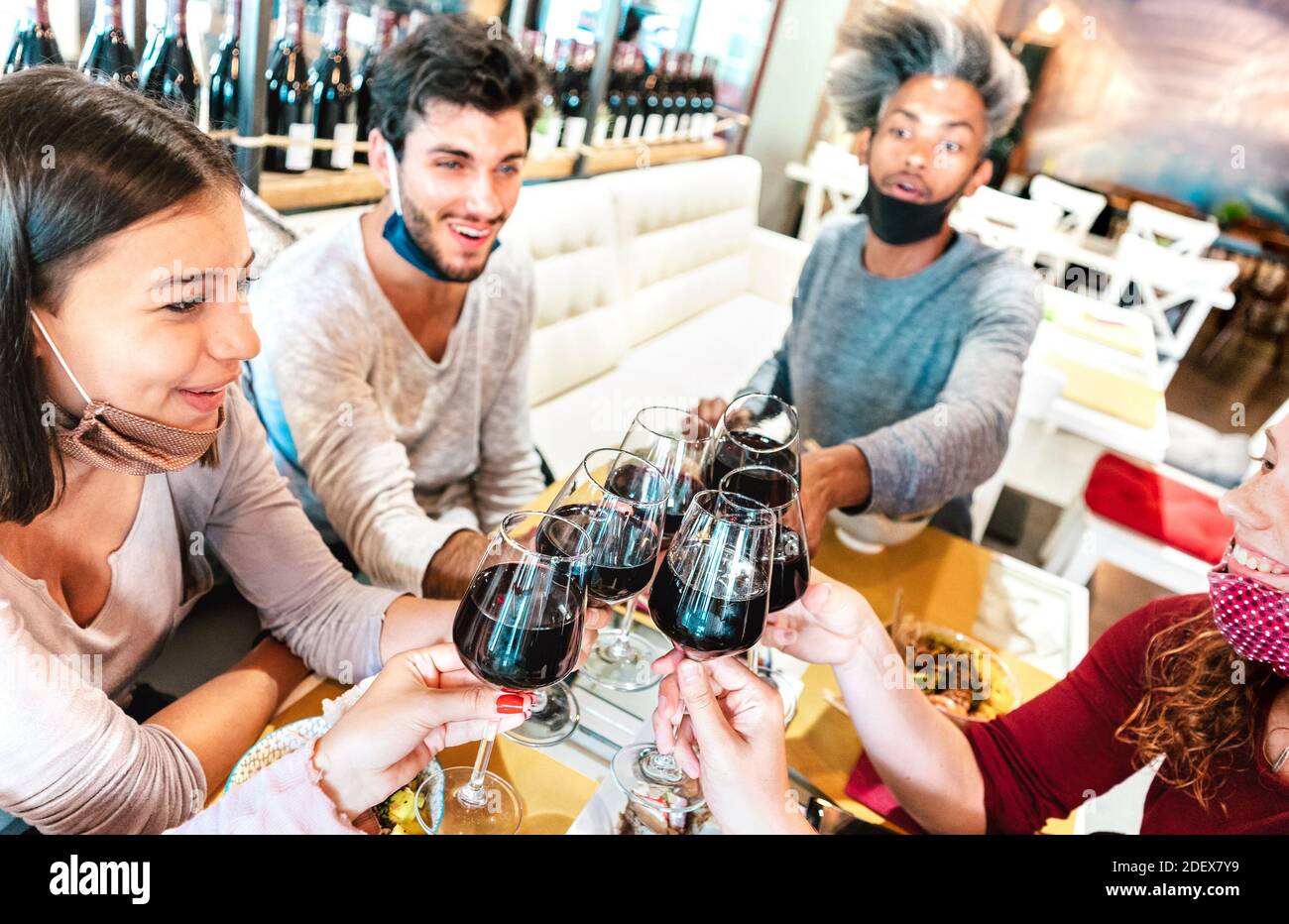 Leute, die Wein im Restaurant mit Gesichtsmasken toasten - Neu Normales Lifestyle-Konzept mit glücklichen Freunden, die Spaß zusammen an Weinbar Stockfoto
