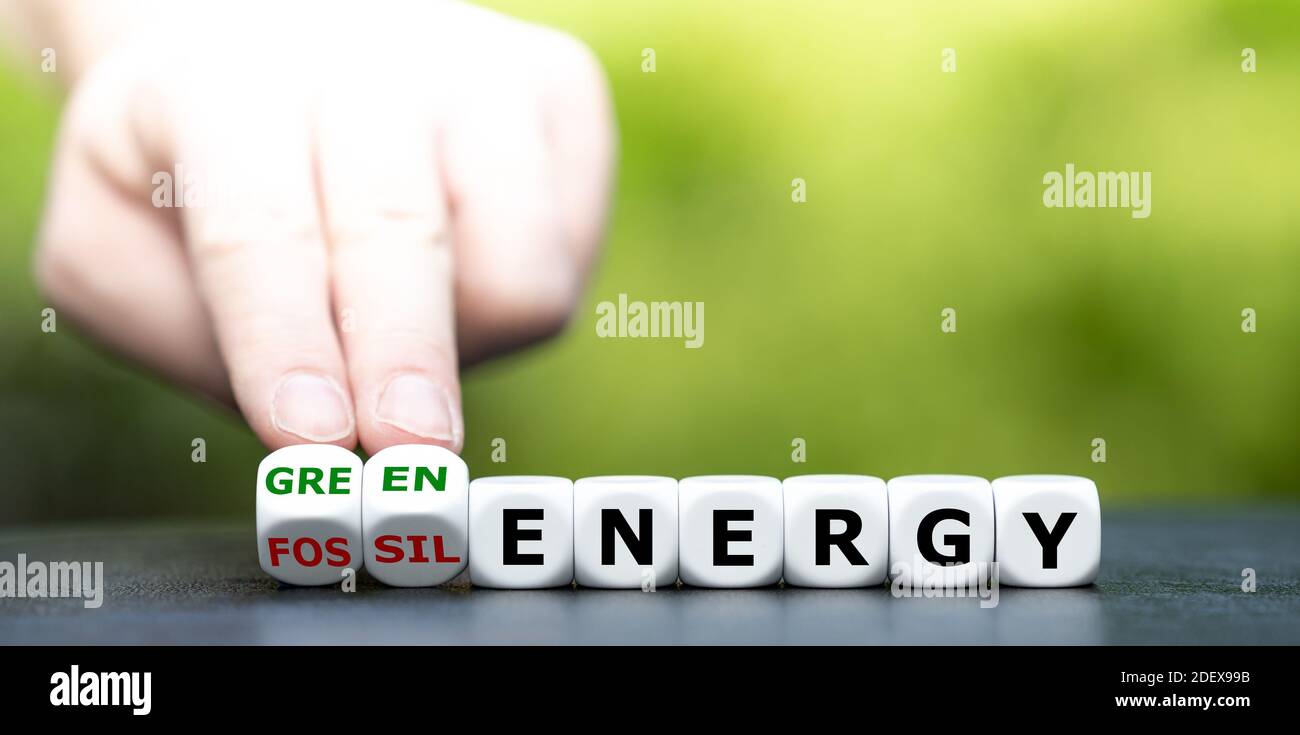 Hand dreht Würfel und ändert den Ausdruck "fossile Energie" in "grüne Energie". Stockfoto