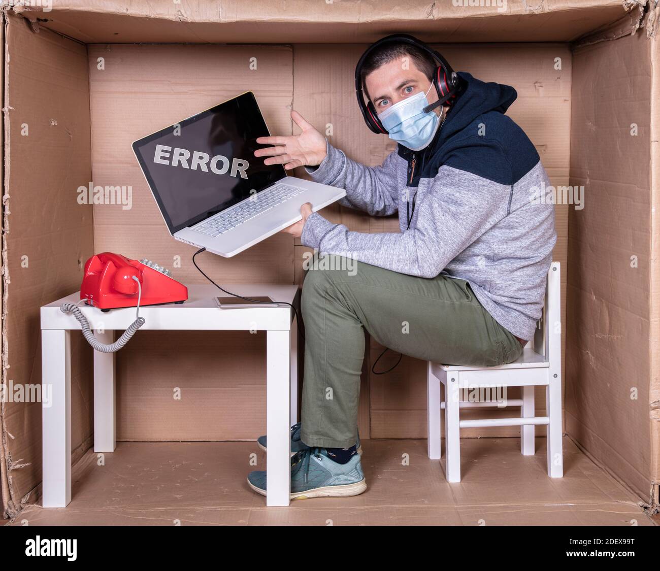 Der Mitarbeiter arbeitet aus seinem eigenen Kartonbüro, um sich zu isolieren Von anderen Stockfoto