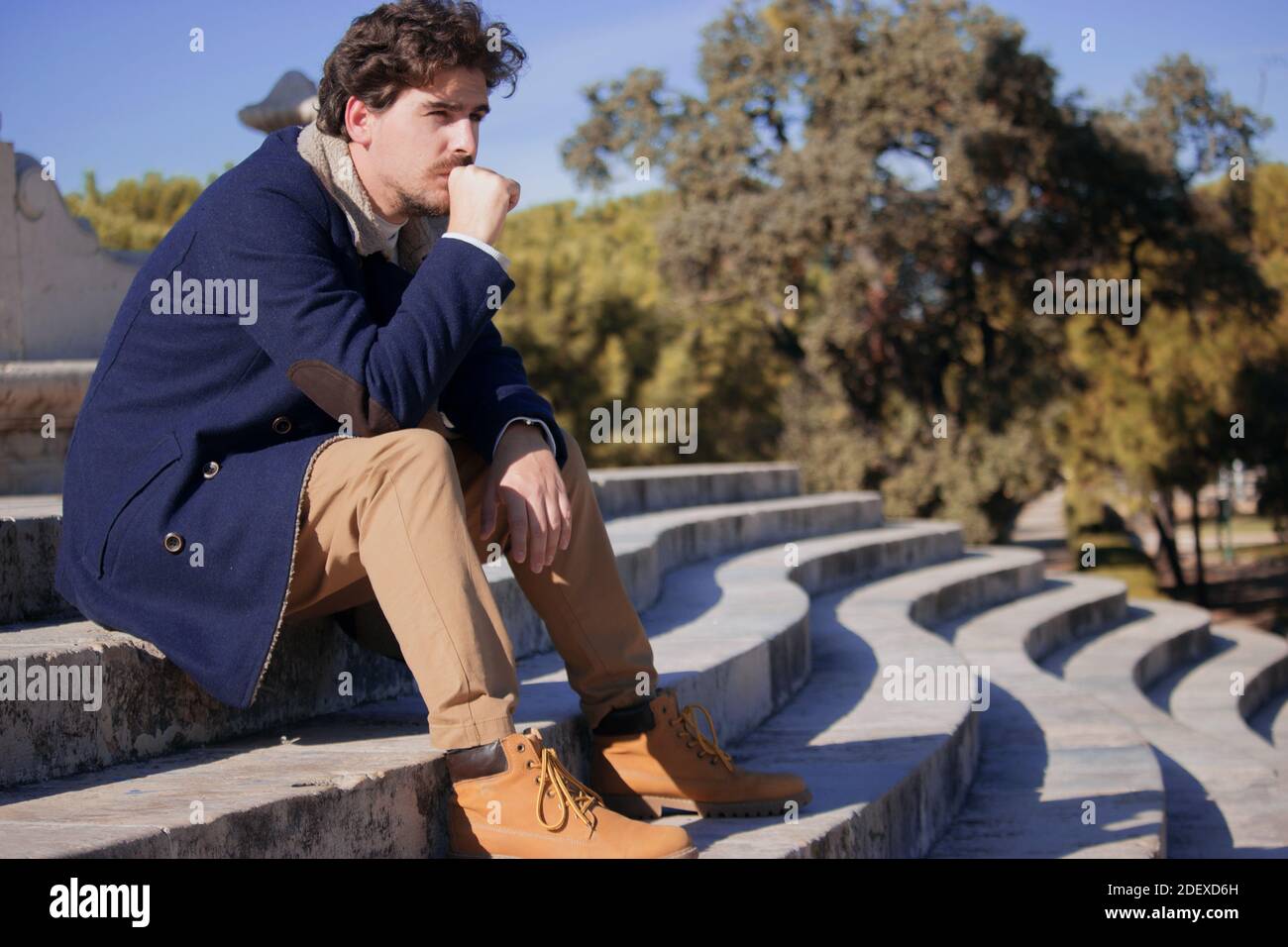 Ein junger Mann im Alter von 24-30 Jahren, der frustriert auf der Straße saß, nachdem er von seinem letzten Job entlassen worden war. Verärgerter Mann verliert seinen Bürojob. Stockfoto