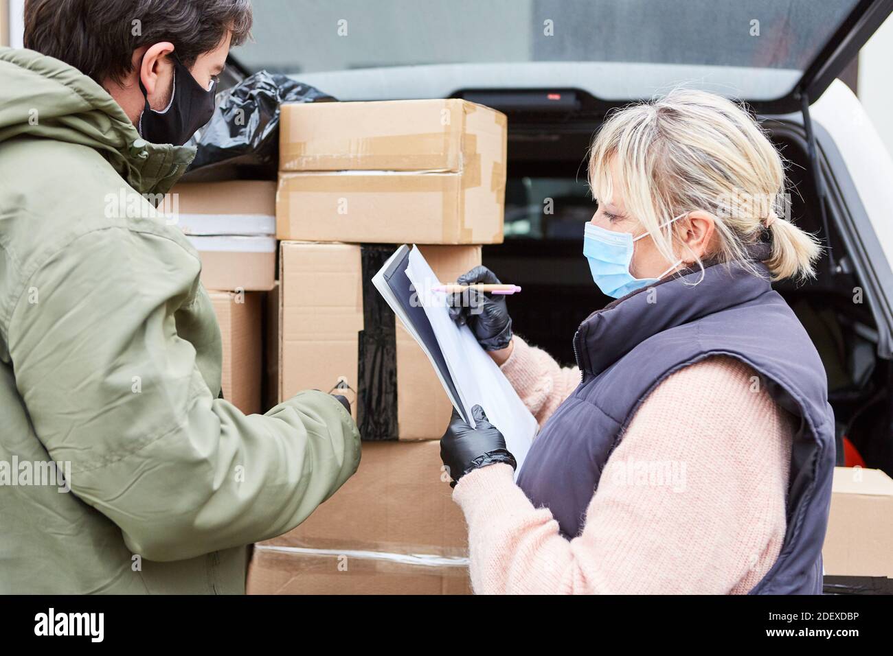 Das Paketdienst-Team überprüft die Lieferungen vor einer offenen Tür Ladefläche mit vielen Paketen Stockfoto