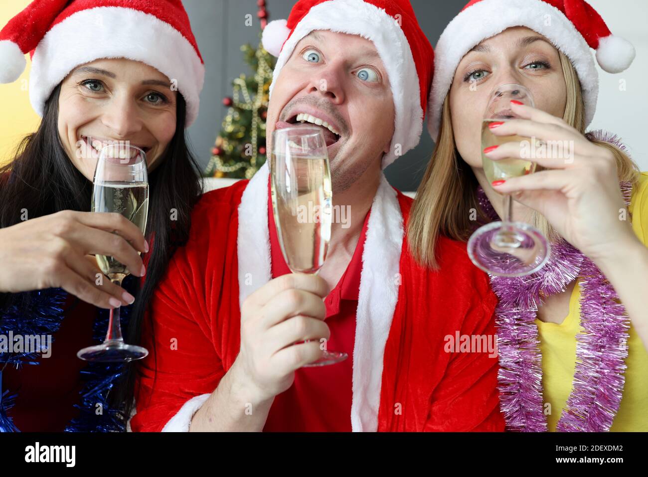 Mann und zwei Frauen in weihnachtsmann Hüte trinken Champagner Für das neue Jahr Stockfoto