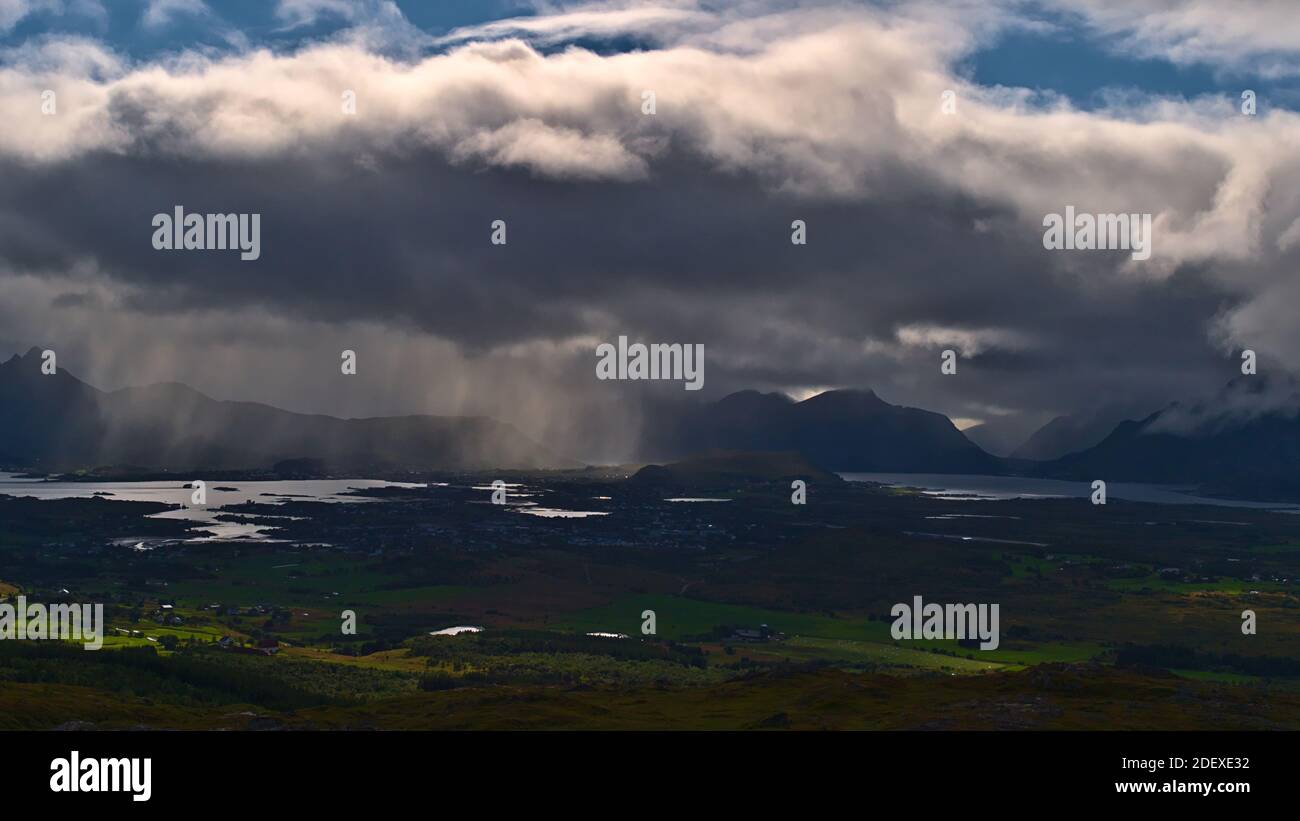 Atemberaubender Panoramablick über den Westen der Insel Vestvågøy, Lofoten, Norwegen mit unbeständiges Wetter, Wolken und sichtbarem Niederschlag über Leknes Stadt. Stockfoto