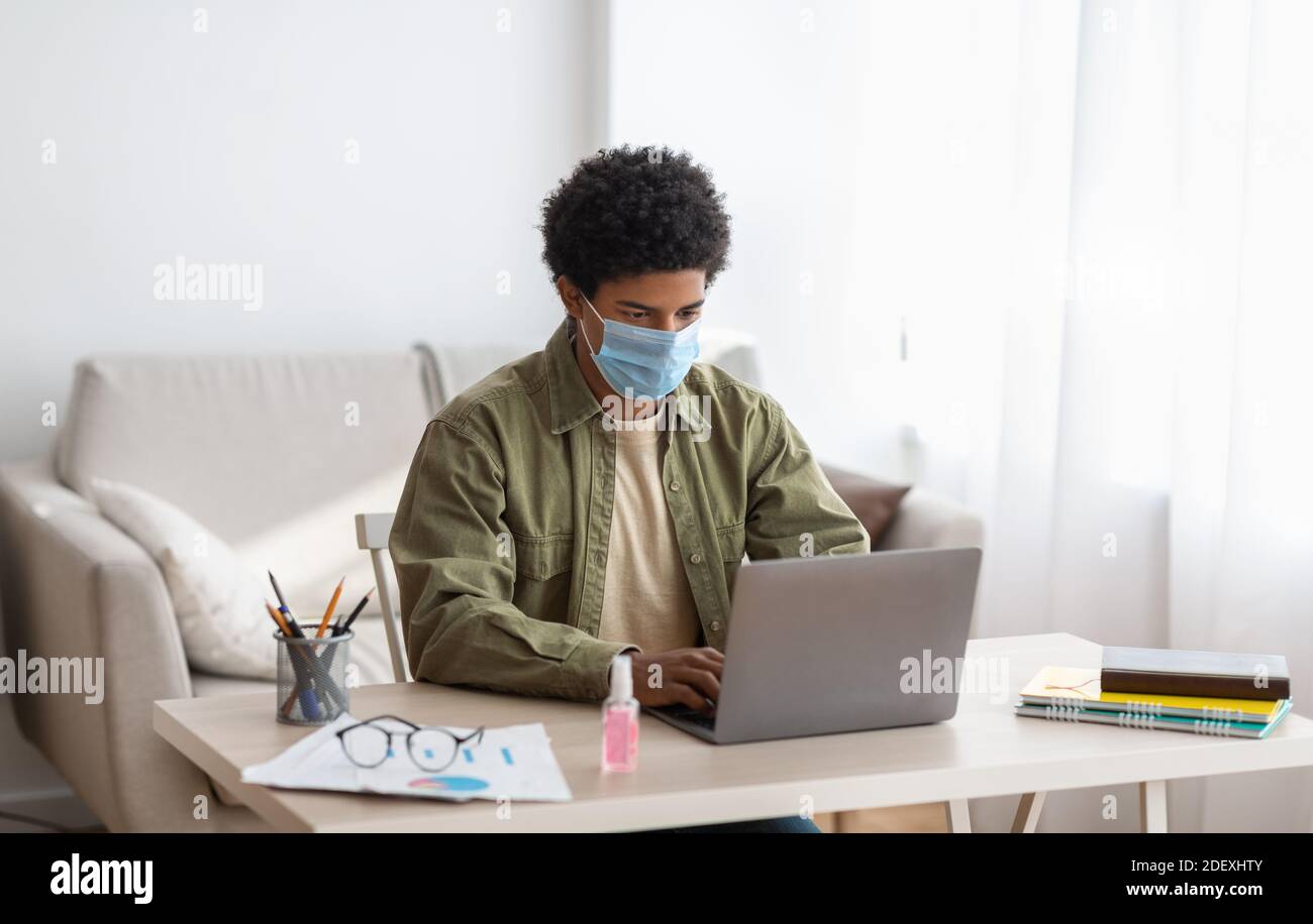 Webbasiertes Lernen während der covid-19 Pandemie. Teenager-Student in Maske Teilnahme Online-Klasse auf Laptop zu Hause Stockfoto