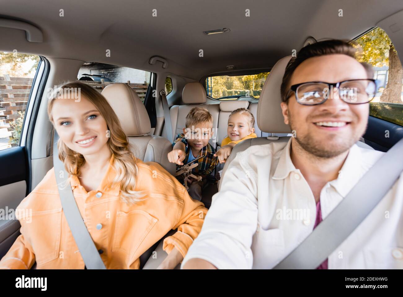 Fröhliche Kinder zeigen mit den Fingern in der Nähe der Eltern auf  verschwommenen Vordergrund Im Auto Stockfotografie - Alamy