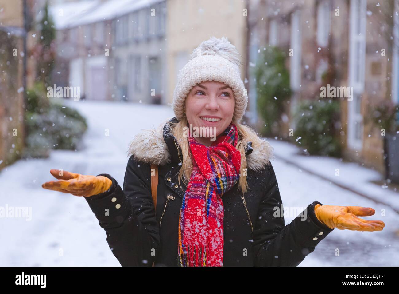 Eine junge Frau freut sich über einen sanften Schneefall in Edinburgh, Schottland Stockfoto