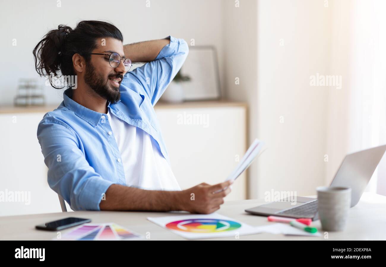 Westlicher Designer, der an der Rezeption mit Farbfeldern arbeitet Heimbüro Stockfoto