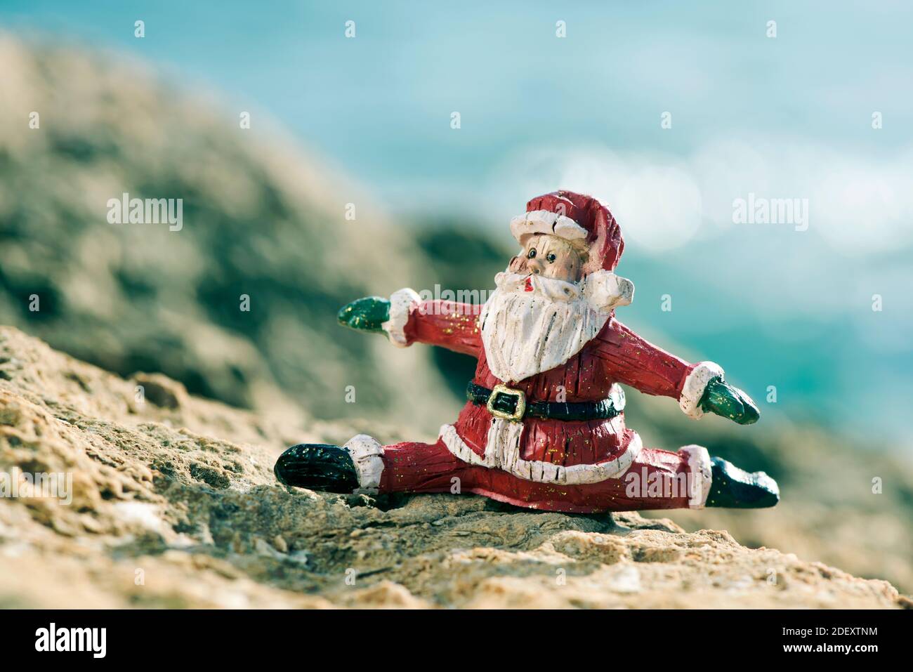 Eine Figur des weihnachtsmannes in einer Spalte auf einem Felsen in einer natürlichen Landschaft, mit dem Ozean im Hintergrund Stockfoto