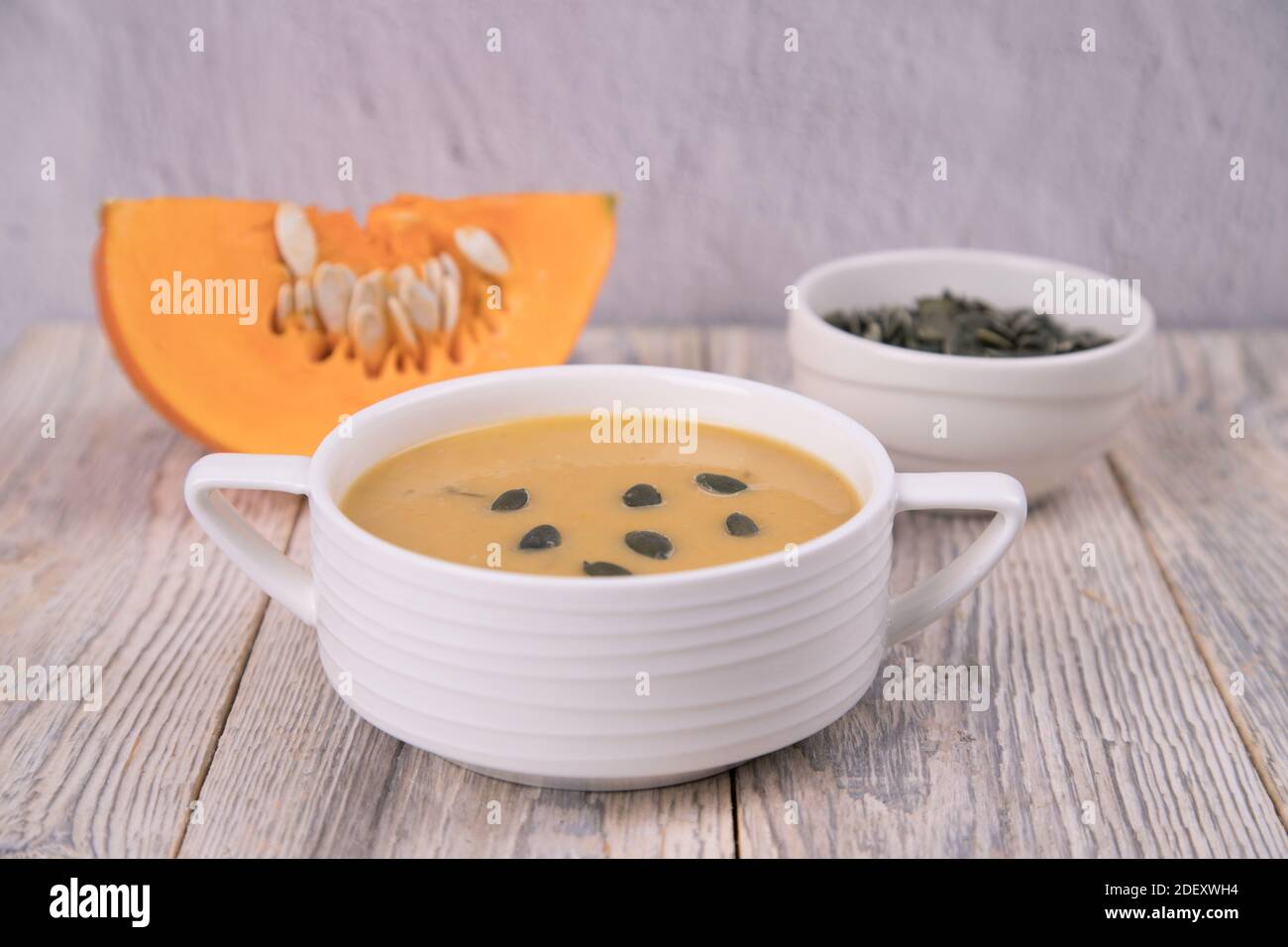 Nahaufnahme auf einem Teller Kürbispüree Suppe, Kürbiskerne und ein Stück Kürbis in Scheiben geschnitten . Stockfoto