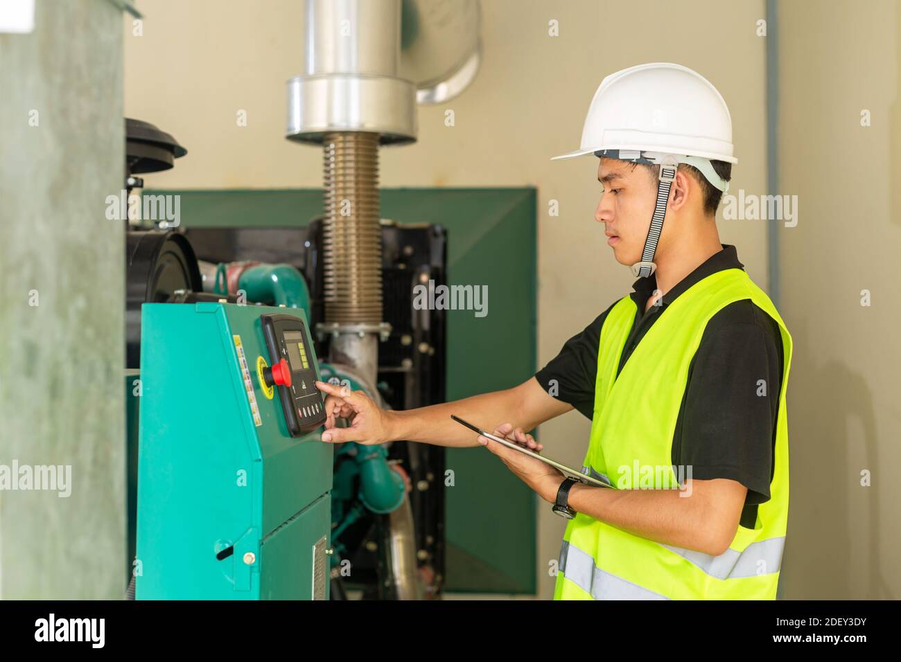 Asiatischer Wartungstechniker, der die technischen Daten der Ausrüstung des Wasserdruckkontrollsystems im Werk überprüft. Stockfoto