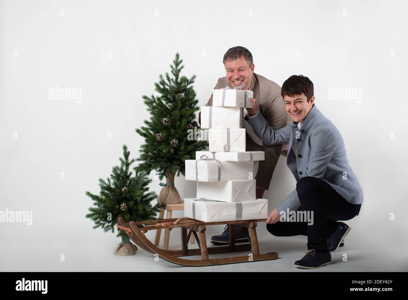 Weihnachten thematisierte horizontale Business-Paar Porträt gekleidet smart casual in blau, weiß, beige Hosen und Blazer auf grauem Hintergrund. Stockfoto