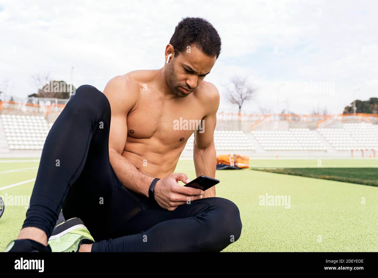 Stock Foto von einem Afro-Sportler, der eine Pause beim Verwenden des Telefons in der Sportstrecke. Stockfoto